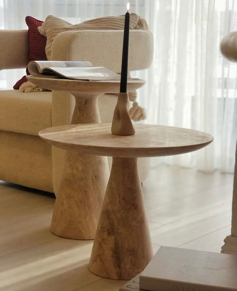 Troia Light Travertine Round End/Side Table Conic Shape Leg Honed (D)18" (H)18.5" installed living room black candle is lit next to window and beige color armchair and beige blanket