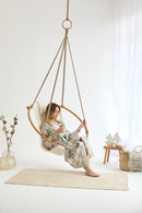twill natural hanging round chair teak frame blonde woman sitting vase wood side table throw blanket