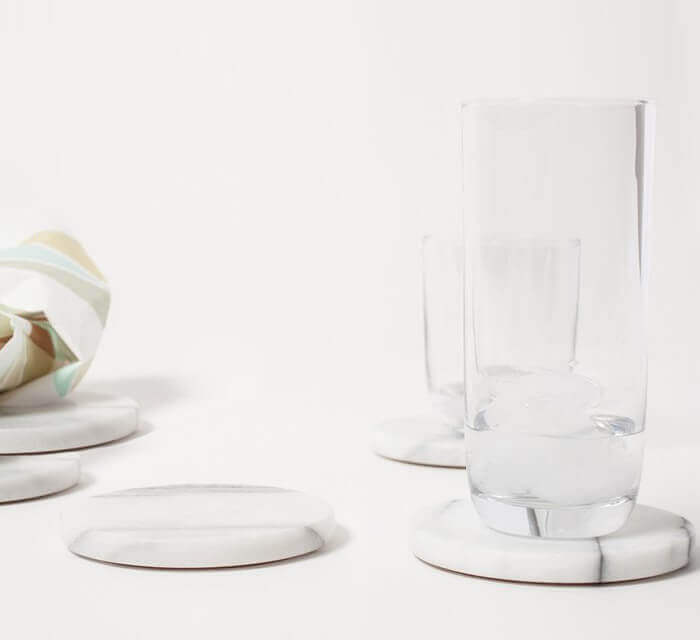 Carrara White genuine marble round coasters 4x4 polished set of product shot glass of water on top