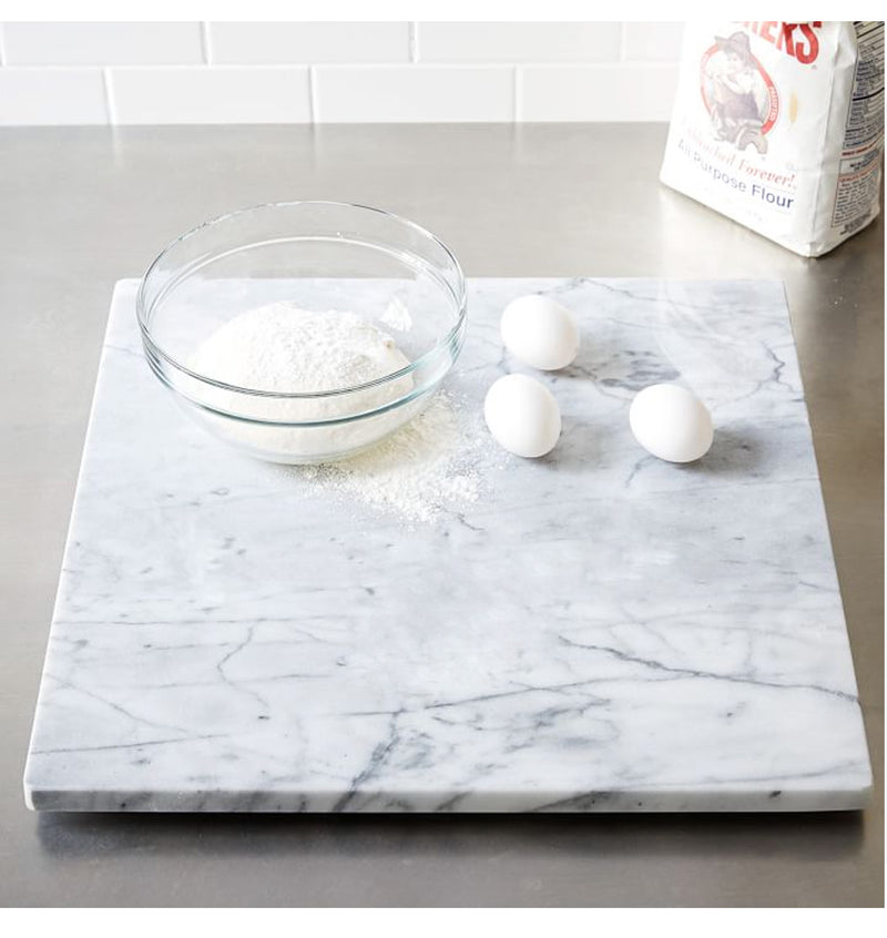 Carrara White genuine marble serving cutting board 14x14 polished product shot 3 eggs and flour in a glass bowl