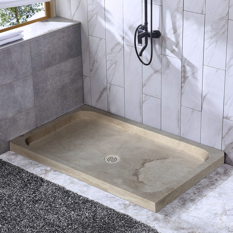 Troia Light Travertine Rectangular Shower Base Hand-carved from Solid Block (W)32" (L)48" (H)3" installed bathroom black wall mount bath faucet window and towels on the left side ceramic tiles on the walls and floor 