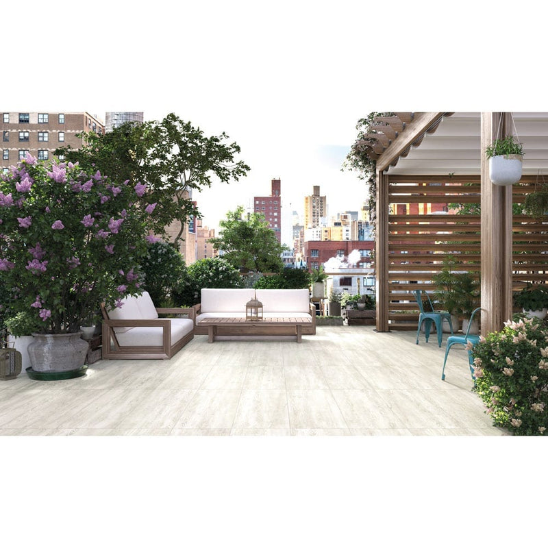 caldera blanca porcelain pavers 16x47in matte floor tile LPAVNCALBLA1647 installed on a terrace of a condo with some nice plants and 2 blue chairs and seating set