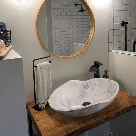 Carrara White Marble Wavy Designer Above Vanity Bathroom Sink (L)24" (W)14" (H)6" installed above wooden vanity round yellow framed large wall mirror and had-town on vanity hung to black metal towel holder