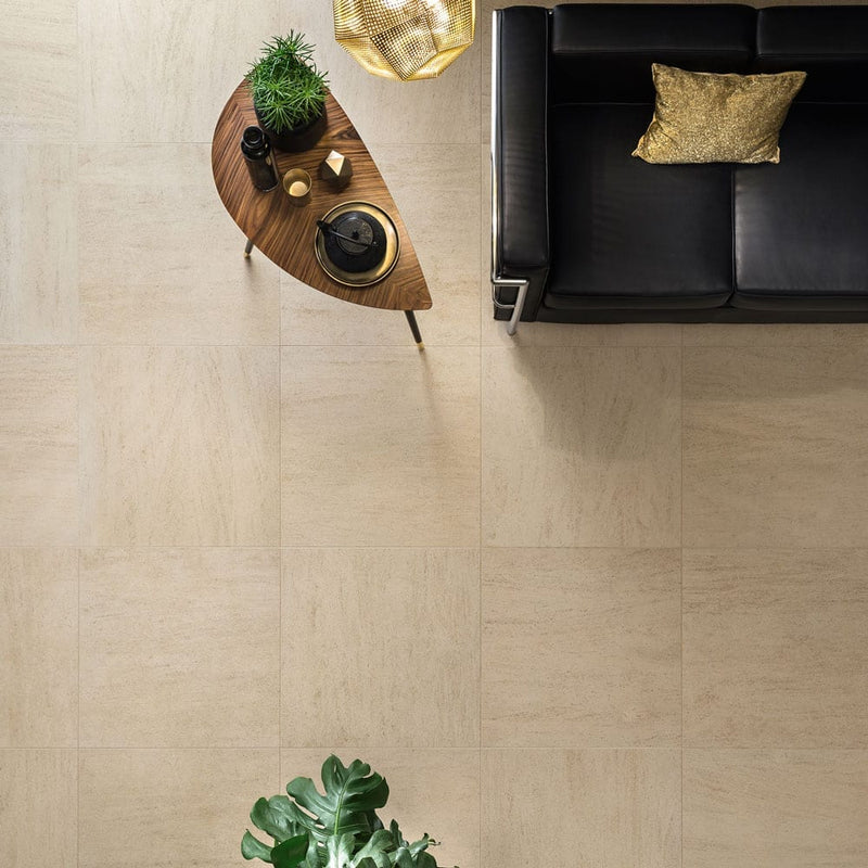 living style beige porcelain pavers 24x24in matte floor tile LPAVNLIVBEI2424 installed on living room floor with a leather coach and a plant