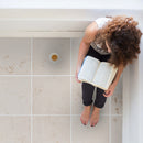 mayra white limestone 24x24 woman sitting reading book closeup